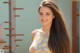 A woman with long brown hair standing in front of a staircase.