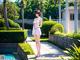 A woman in a white dress standing next to a pool.