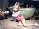 A girl sitting on the ground next to a bathtub.