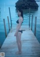 A woman in a bikini standing on a wooden dock.