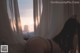 A woman laying on a bed in front of a window.