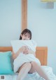 A woman sitting on a bed holding a pillow.